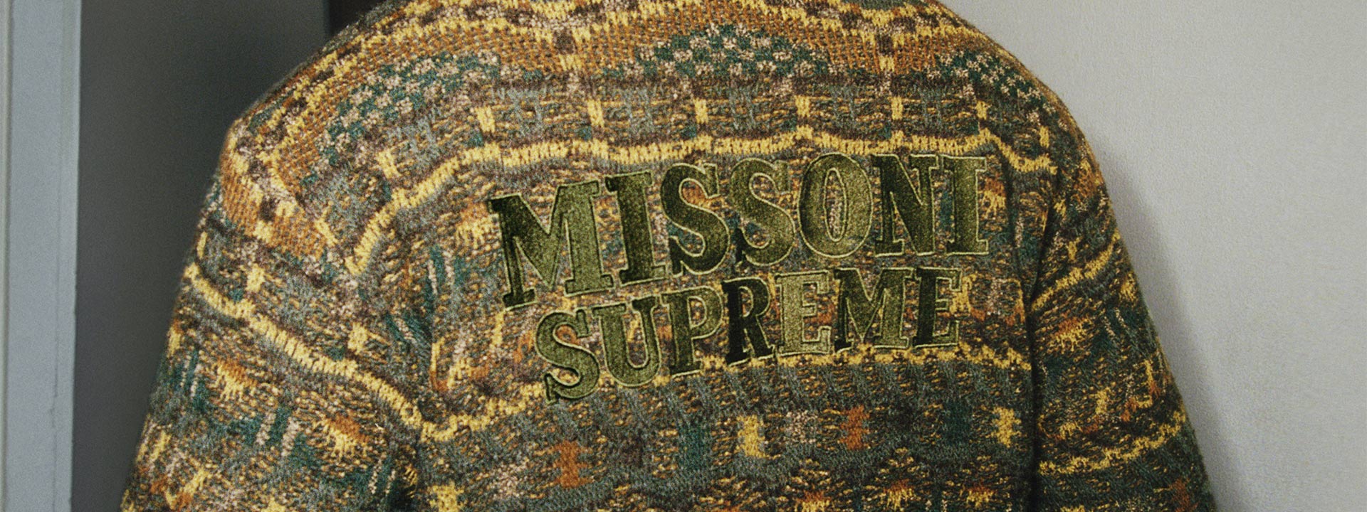  The model who is seen from the back is wearing a green jacket with interesting motifs.